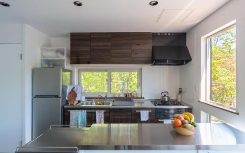 a kitchen with a refrigerator and a counter with a bowl of fruit at Forest Hideaway in Niseko
