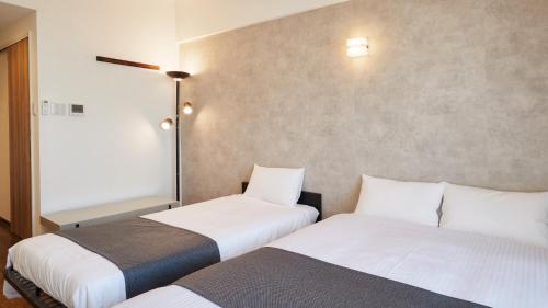 two beds sitting next to each other in a room at New Normal Hotel in NAMINOUE ニューノーマルホテルイン波の上 in Naha