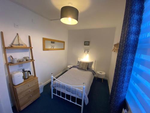 a small bedroom with a bed and a lamp at Rooms At Babbacombe in Torquay