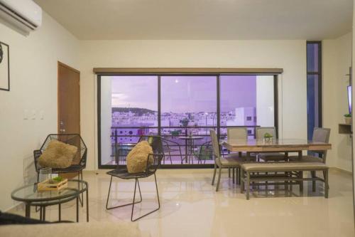 a room with a table and chairs and a large window at Departamento Atlántico Alberca y Casa Club in Mazatlán