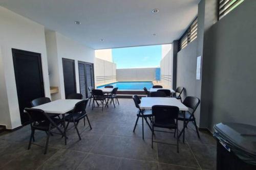 a dining room with tables and chairs and a pool at Departamento Atlántico Alberca y Casa Club in Mazatlán