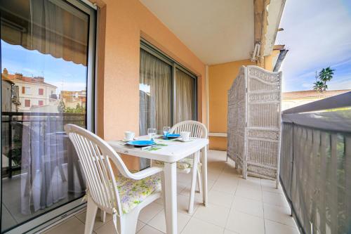 une table blanche et des chaises sur un balcon dans l'établissement Appartement Les Allées, à Cannes