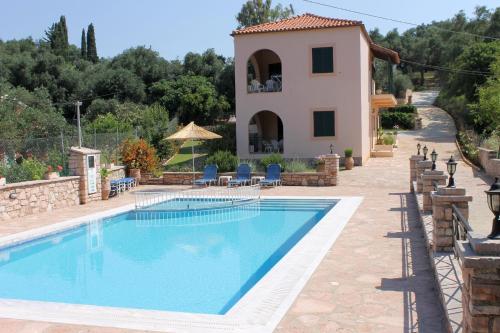 a pool in front of a house with a villa at Emily's Apartments in Kassiopi