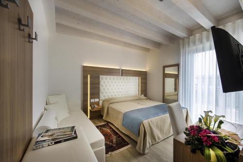 a bedroom with a bed and a desk and a television at Hotel Hollywood***S in Lido di Jesolo