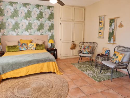 - une chambre avec un lit et deux chaises dans l'établissement La villa des cannes, à Sainte-Marie