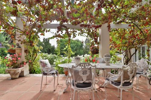a patio with a table and chairs under a pergola at Three Oaks in Durbanville