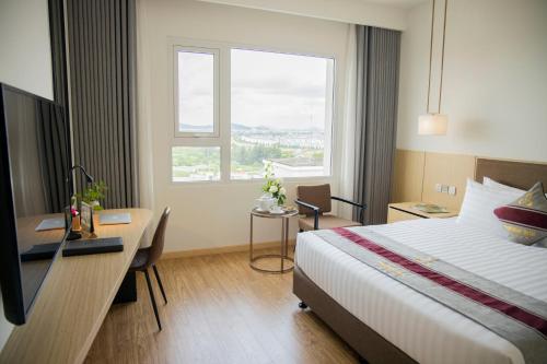 a hotel room with a bed and a desk and a window at Pearl River Hotel in Hai Phong