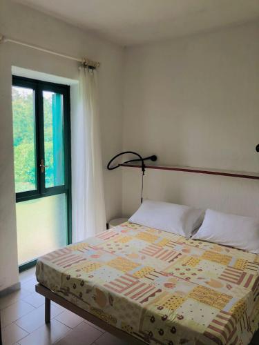 a bed in a bedroom with a window at NRH Stintino Beach Garden in Stintino