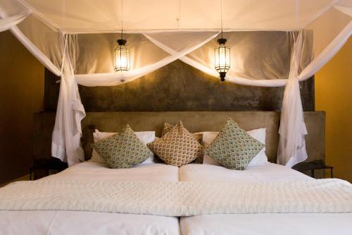 a bedroom with a white bed with pillows at Olive Grove Guesthouse in Windhoek