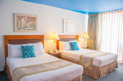 a hotel room with two beds with blue pillows at Holiday Surf Hotel (with full kitchen) in Honolulu