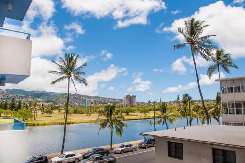 uma vista para um corpo de água com palmeiras em Holiday Surf Hotel (with full kitchen) em Honolulu