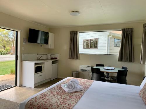 a bedroom with a bed and a kitchen and a table at Omarama TOP10 Holiday Park in Omarama
