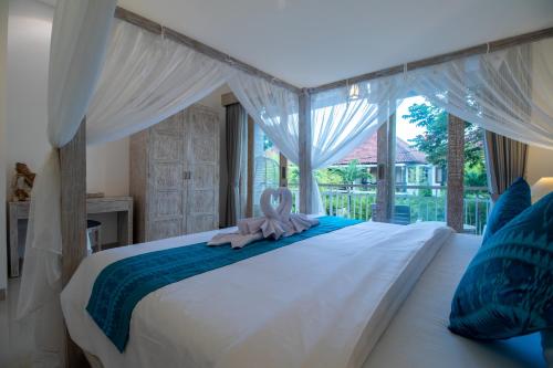 Un dormitorio con una cama blanca con una toalla rosa. en Sayang Sanur Duplex en Sanur