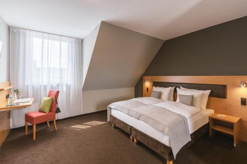 シュトゥットガルトにあるNovum Hotel Bruyのベッドルーム1室(大型ベッド1台、赤い椅子付)