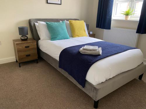 a bedroom with a bed with blue and yellow pillows at Peak House in Ilkeston