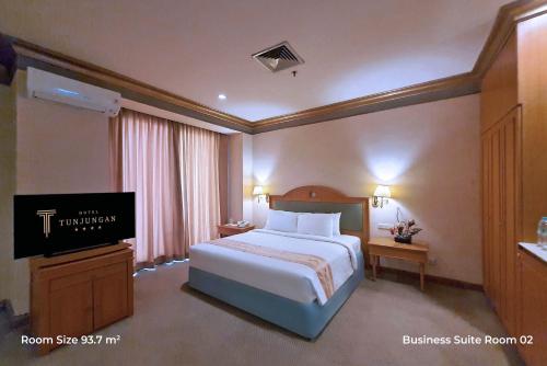 a bedroom with a bed and a flat screen tv at Tunjungan Hotel in Surabaya