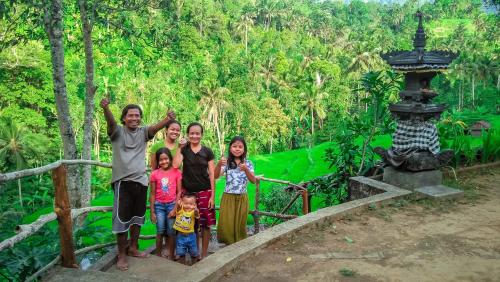 a family posing for a picture in front of a forest at Buda's Homestay Lemukih in Buleleng
