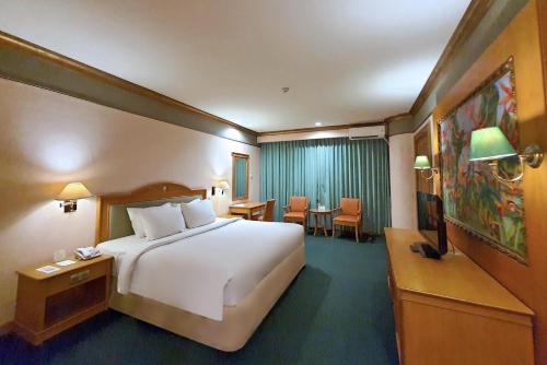 a hotel room with a large bed and a television at Tunjungan Hotel in Surabaya