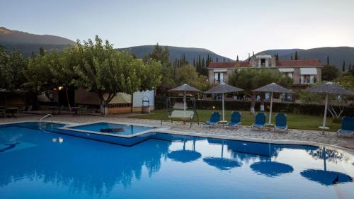 a large swimming pool with blue chairs and a house at Stalaktites Studios in Sami