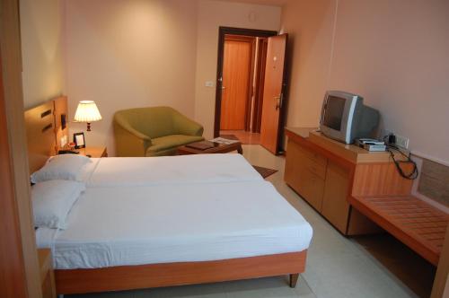 a hotel room with a bed and a tv at Savoy Greens Karnal in Karnal