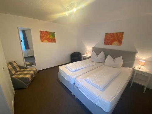 a bedroom with a white bed and a chair at FeWo im Camp Am Wasser in Juliusruh