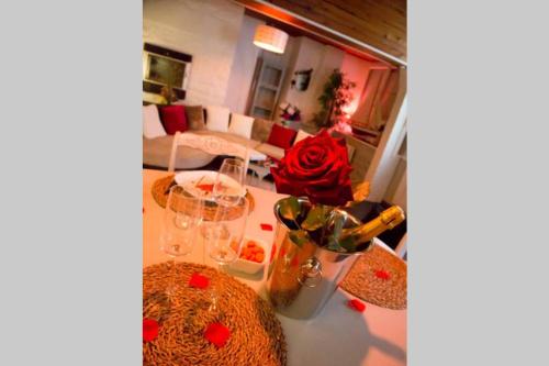 a living room with a table with glasses and a rose at Gîte Love Dream - Le Gîte Romantique in Ger