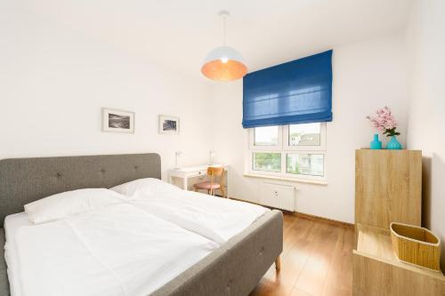 een slaapkamer met een wit bed en een blauw raam bij APT Nadmorskie - Solne in Kołobrzeg