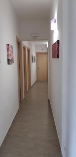 a hallway with white walls and a long hallway with paintings at Arricàmpati Airport Home & Bringo Car Rental in Carini