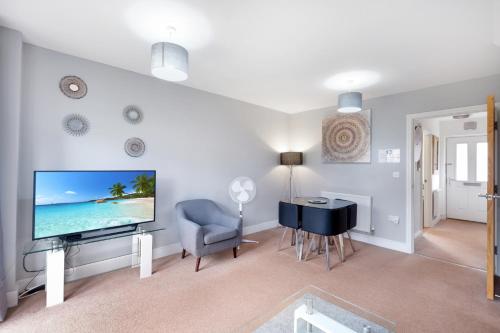 a living room with a television and a table and a chair at London Heathrow Living Holywell Serviced Houses - 3 and 4 bedrooms By Ferndale in Stanwell