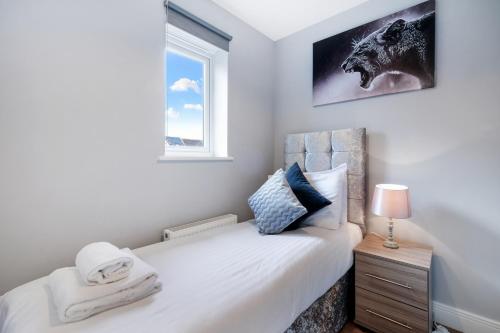a bedroom with a bed with a nightstand and a window at London Heathrow Living Holywell Serviced Houses - 3 and 4 bedrooms By Ferndale in Stanwell