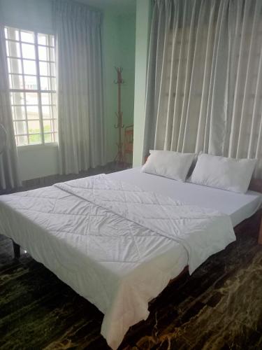 a large white bed in a room with windows at KOL House in Phnom Penh