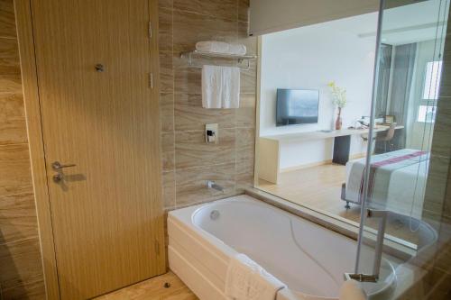 a bathroom with a tub and a television in it at Pearl River Hotel in Hai Phong
