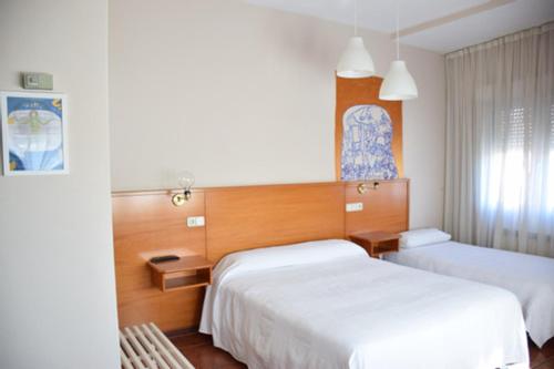 um quarto de hotel com duas camas e uma janela em Hotel Brial em Perillo