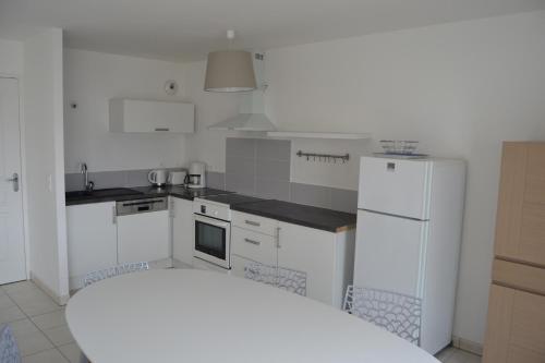 Il comprend une cuisine équipée d'appareils électroménagers blancs et d'un réfrigérateur blanc. dans l'établissement pleneuf val andre appart vue mer 2 à 4 personnes, à Pléneuf-Val-André