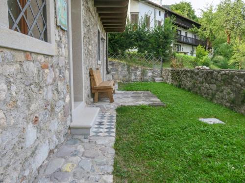 un patio trasero con una pared de piedra y un banco en Apartment Cjase dai Fornasirs by Interhome en Raveo