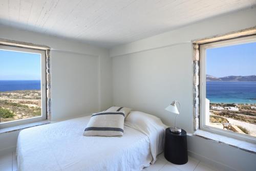 a white bedroom with a bed and two windows at Koufonisi Villas in Koufonisia