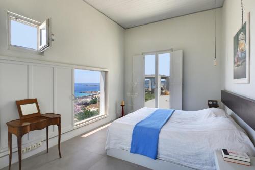 a bedroom with a bed and a desk and windows at Koufonisi Villas in Koufonisia