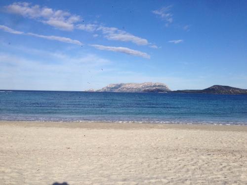 a beach with a view of the ocean and mountains at Domus de Diana in Olbia