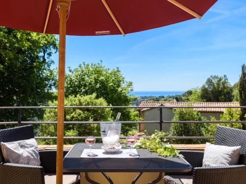 - une table avec des verres à vin et un parasol sur le balcon dans l'établissement Apartment Olive by Interhome, à Vence
