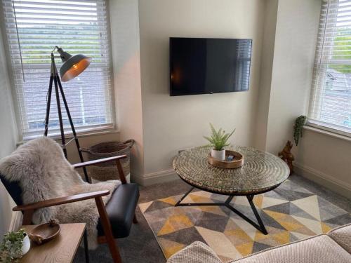 a living room with a table and a tv at The Hive at Poppi-Red in Hawkshead