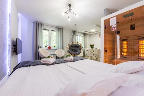 a large white bedroom with a large bed and two chairs at Apartamenty hoteLOVE z sauną in Karpacz