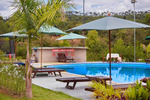 a swimming pool with benches and umbrellas next to a pool at Andasibe Lemurs Lodge in Andasibe