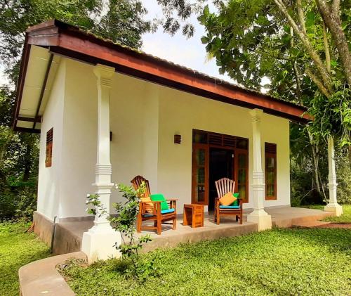 a small white house with two chairs and a table at Jackland Holiday Cabanas in Demanhandiya