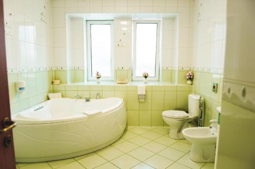 a bathroom with a tub and a toilet and a sink at Hotel Senator in Slatina