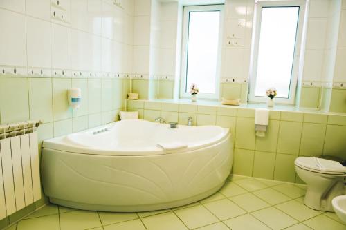 a white bathroom with a tub and a toilet at Hotel Senator in Slatina