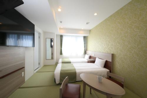 a hotel room with a bed and a table at Kuretake Inn Premium Numazu Kitaguchi Ekimae in Numazu
