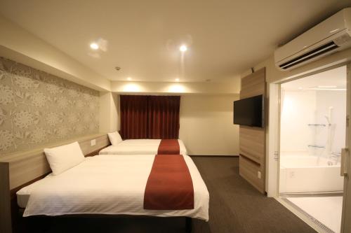 a hotel room with two beds and a bath tub at Kuretake Inn Premium Numazu Kitaguchi Ekimae in Numazu