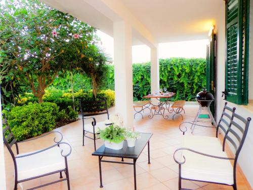 a patio with chairs and a table and trees at Villa Oleandro in Scopello