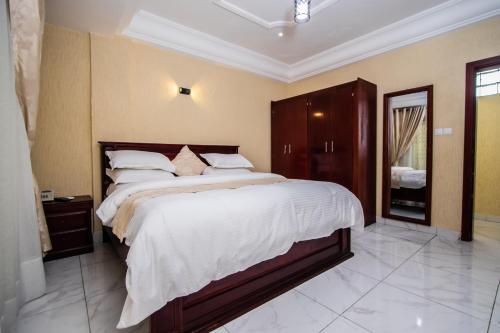 um quarto com uma cama grande e lençóis brancos em Residence Le Bonheur - Serviced apartment by Douala Airport/Mall em Douala
