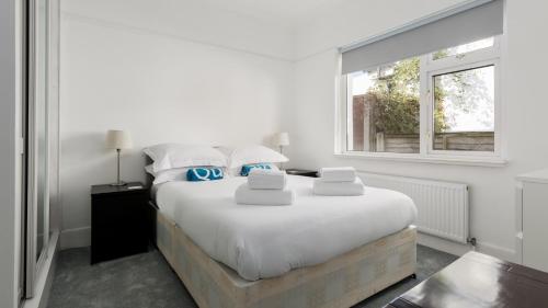 a white bedroom with a large bed and a window at Lake Retreat in Poole